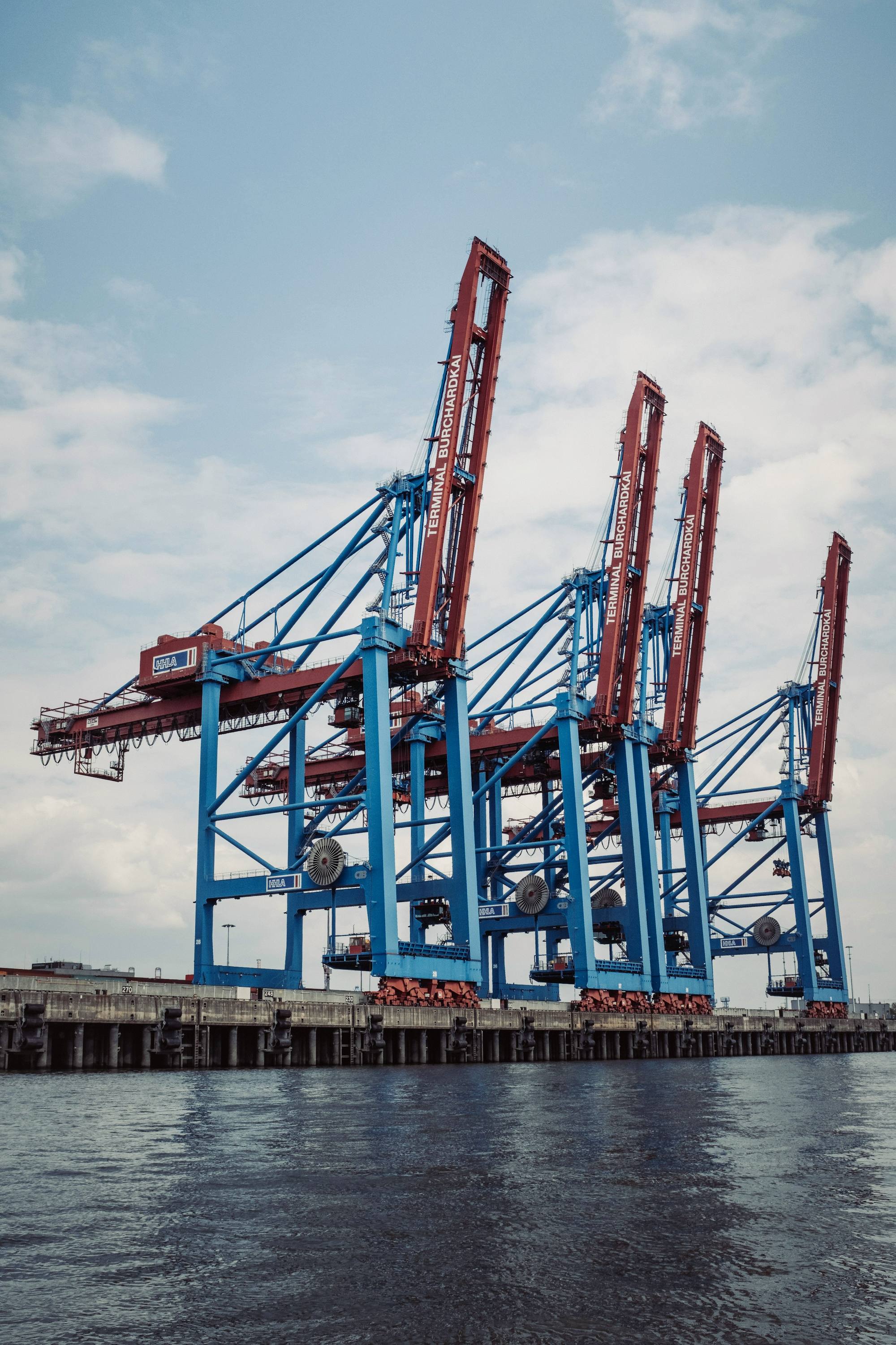 Blue and red harbour cranes against a bright sky