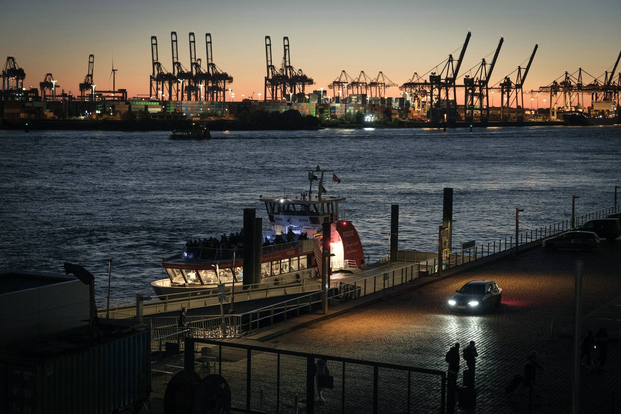 Port cranes at dusk across a wide river