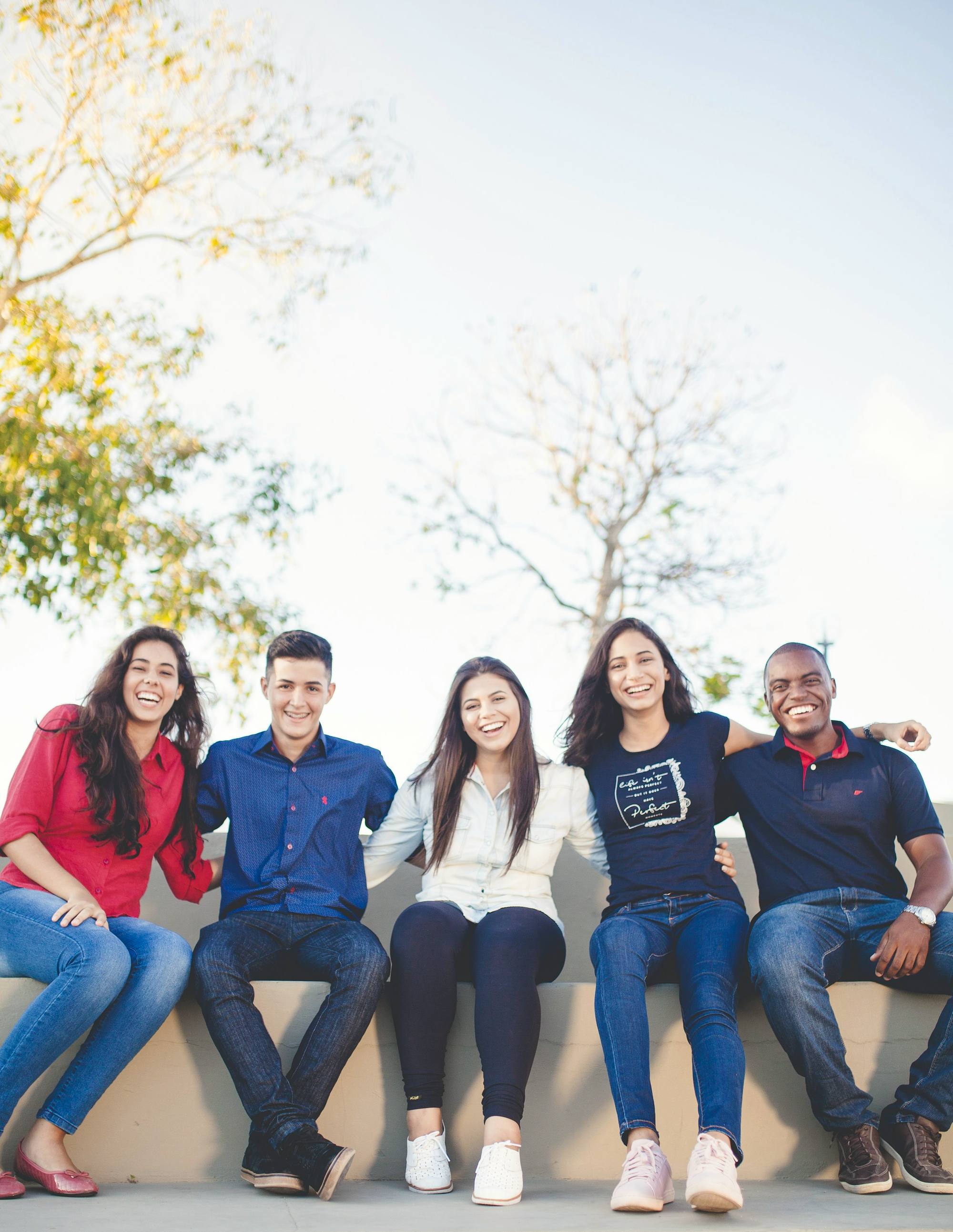 A group of young people sitting together outdoors, smiling