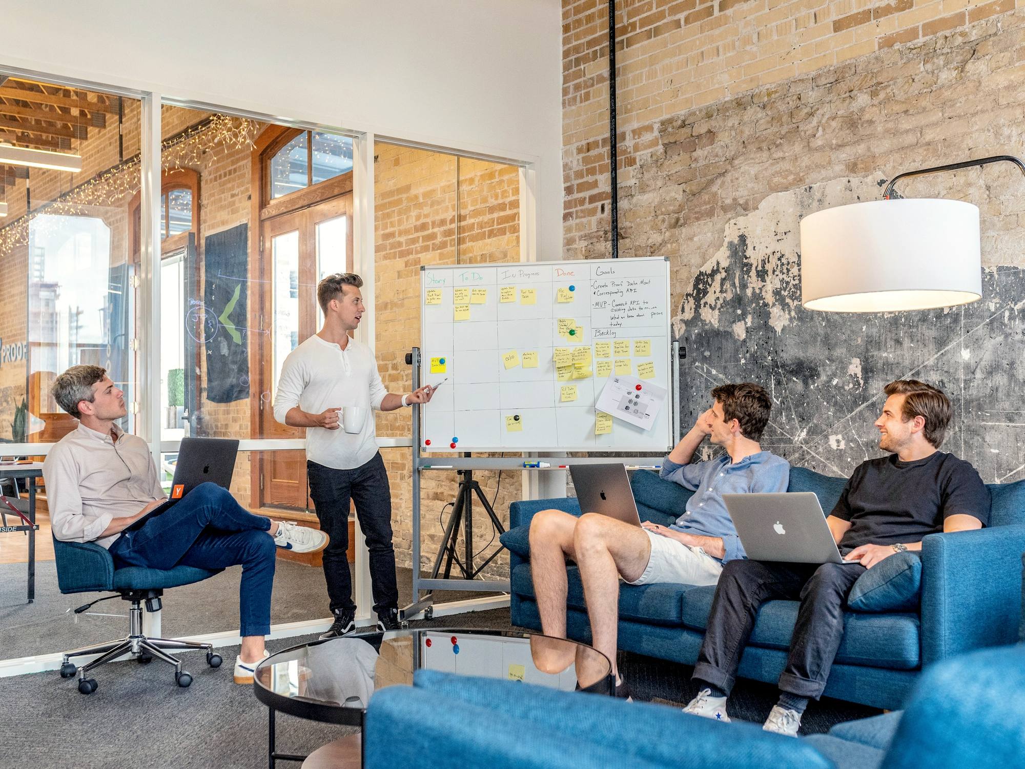 A team meeting in a relaxed office, one person presenting at a whiteboard