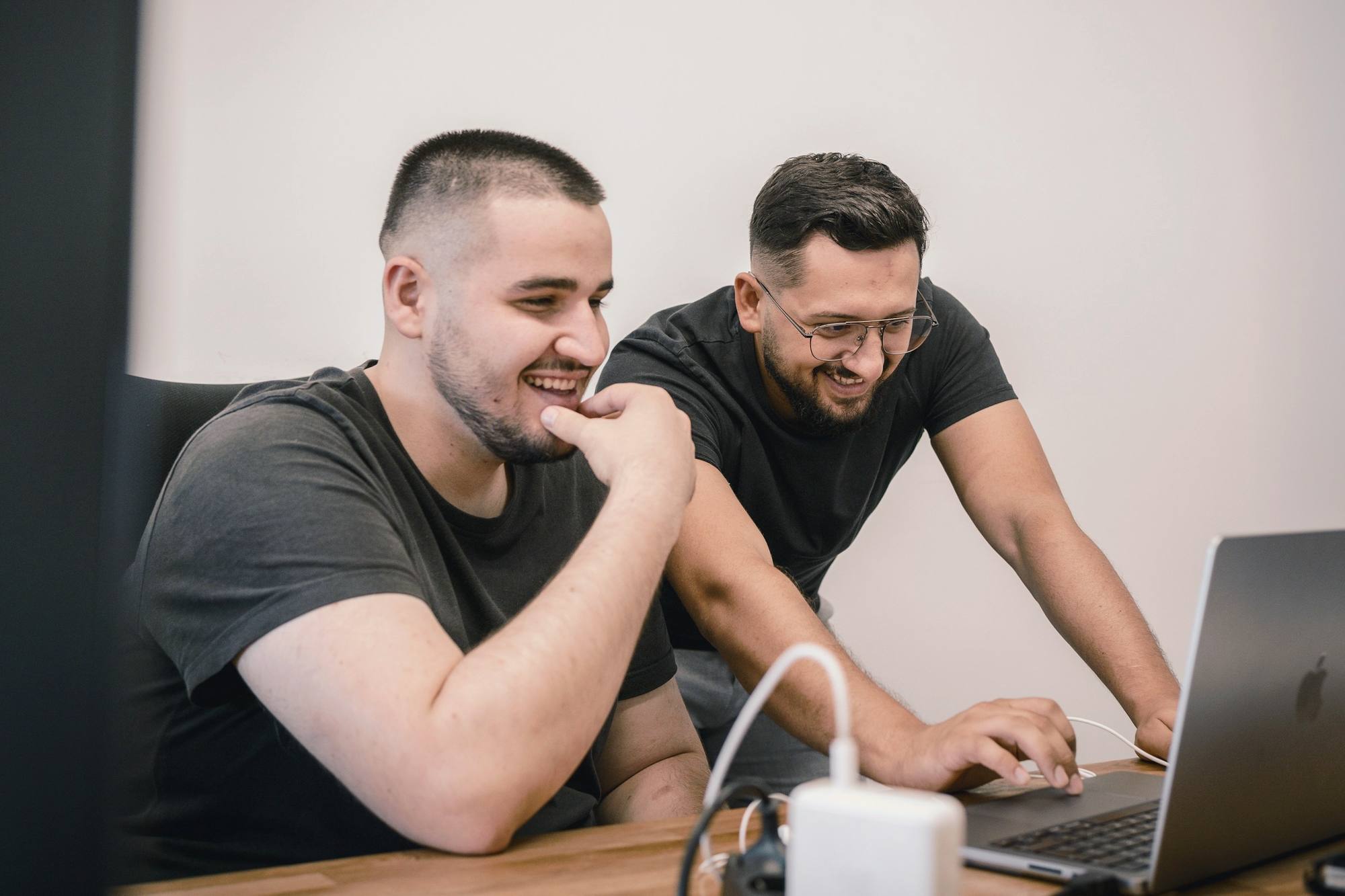 Two colleagues laughing while working on a laptop